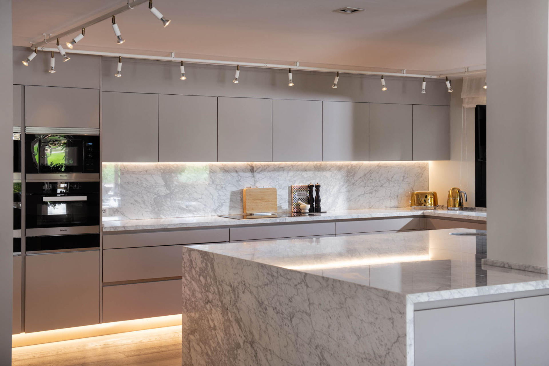 The kitchen with streamlined cabinetry, veined light stone and a central island.